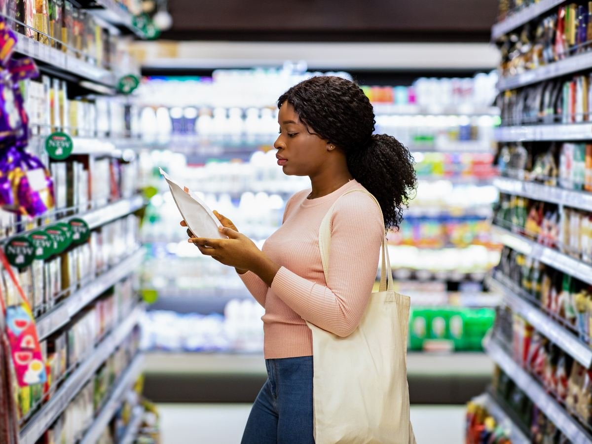 Shopper reading the front of a food package in a grocery aisle