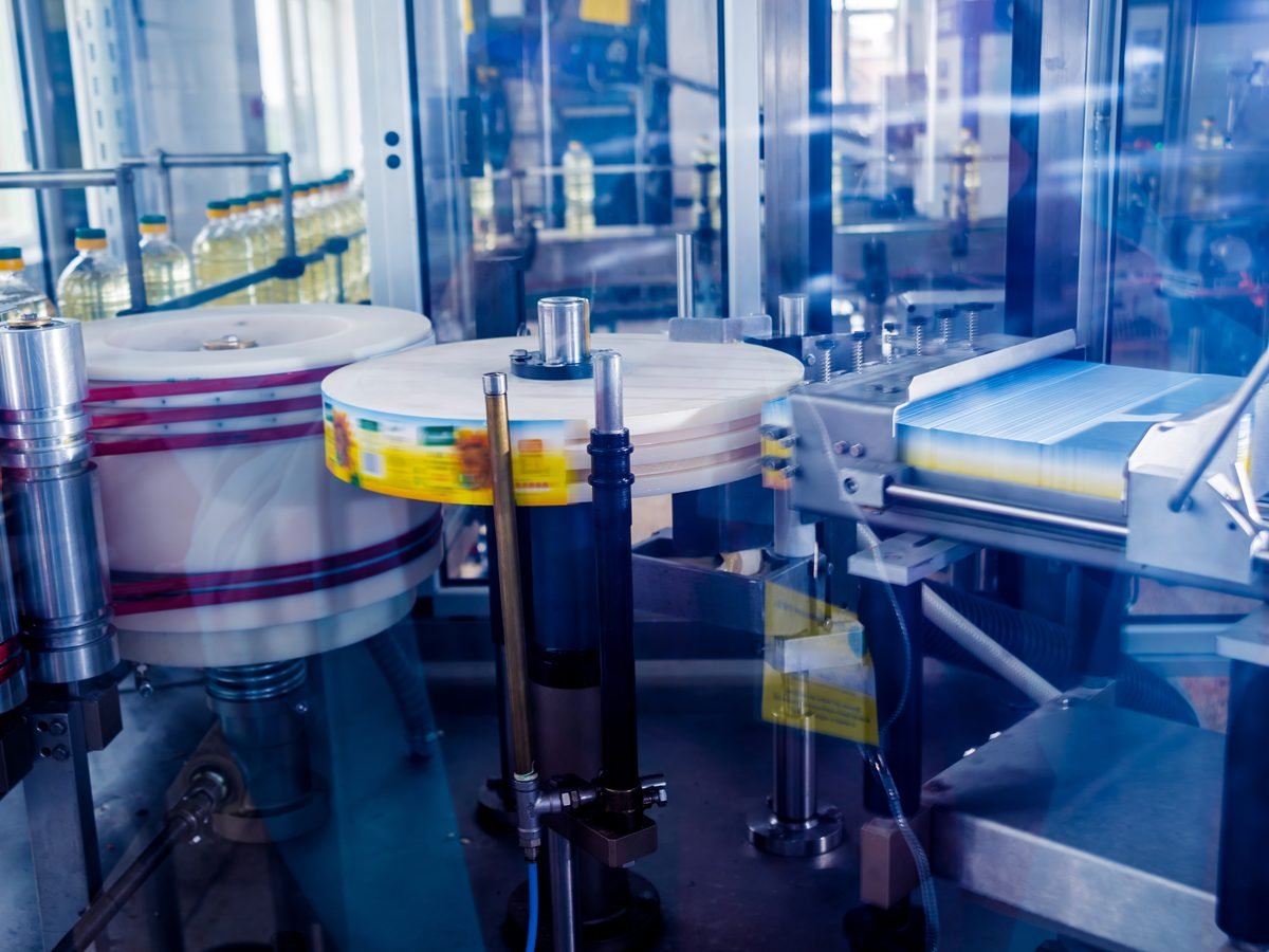 Labelling machine applying rolls of film on a factory production line