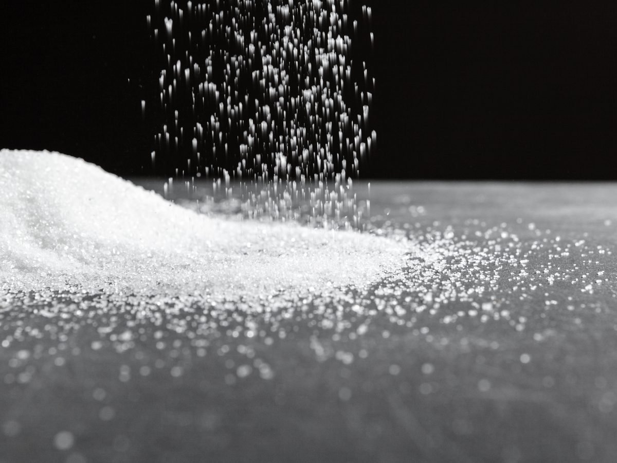 White sugar pouring down onto a mound against a black background